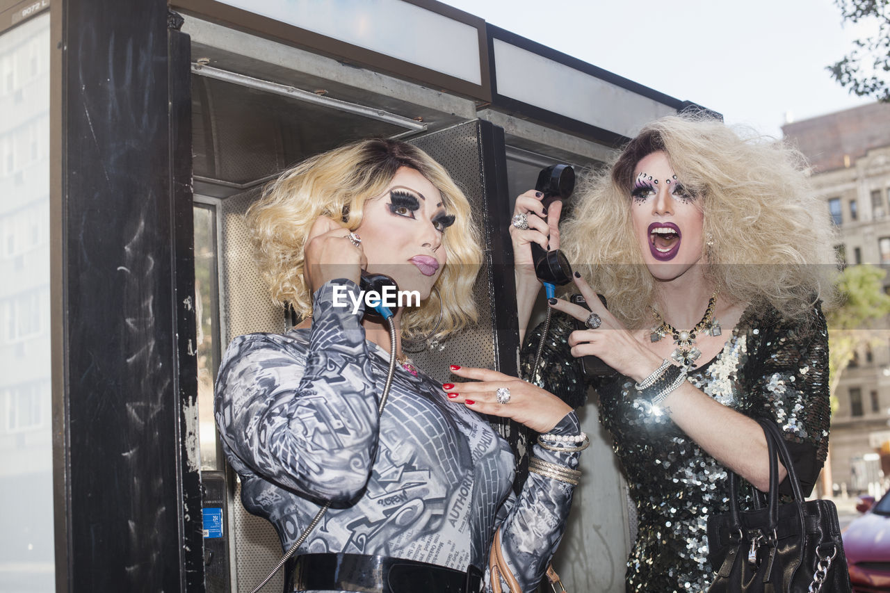 Two drag queens using a payphone