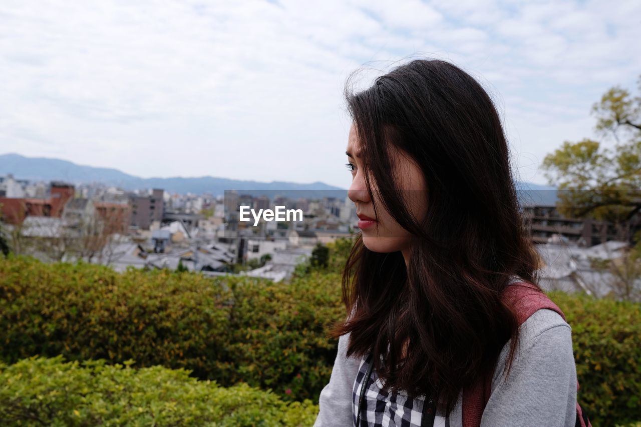Portrait of beautiful woman standing against cityscape