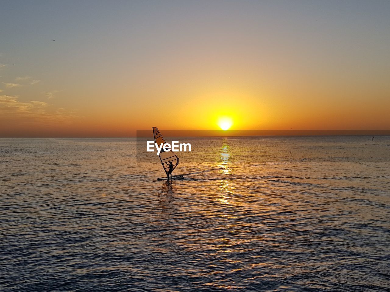 Silhouette person in sea against sky during sunset