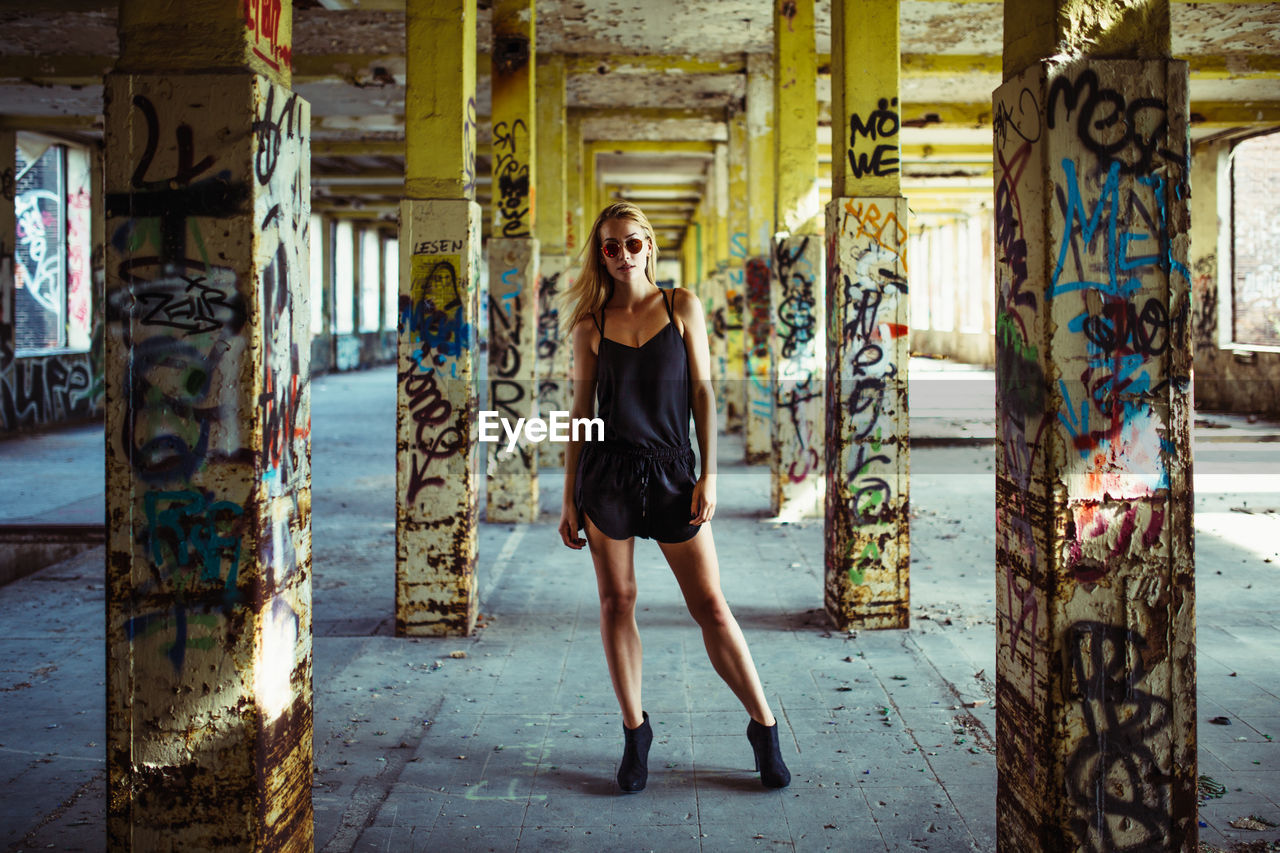 Portrait of young woman in abandoned, graffitied buidling