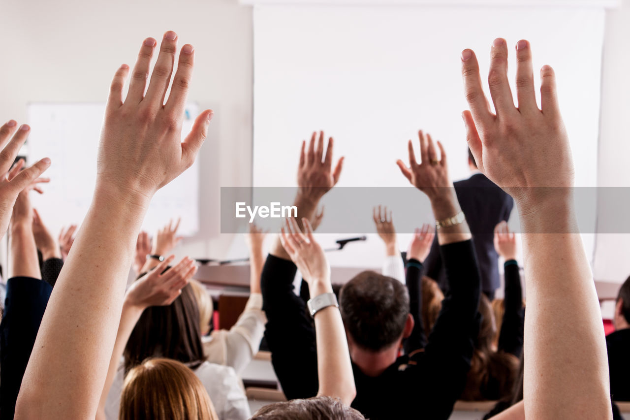 People with arms raised in lecture hall during seminar