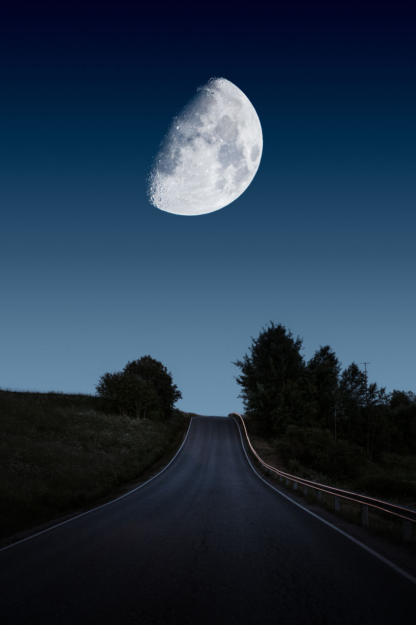 View of road against clear sky at night with huge moon