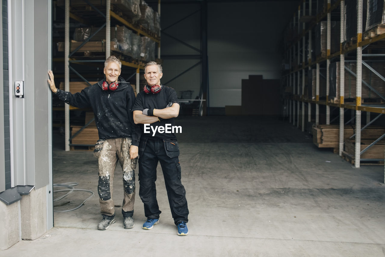 Full length portrait of confident workers standing in entrance at industry