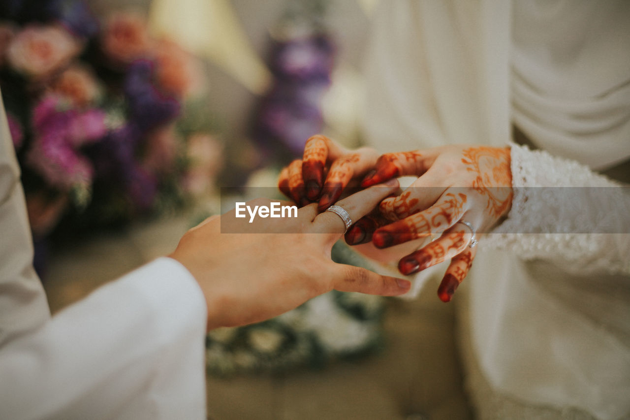 Close-up of bride wearing ring to bridegroom during wedding