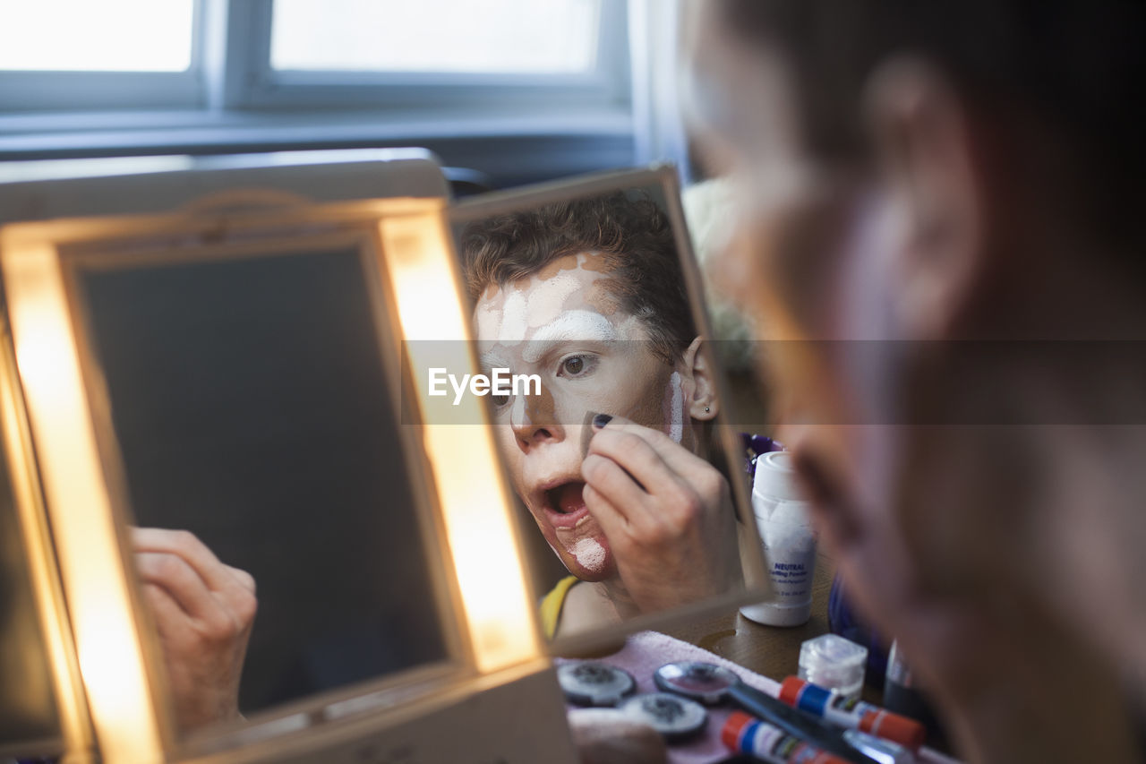 Man applying drag makeup in mirror