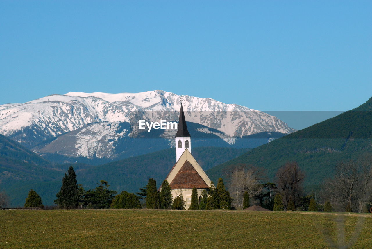 Scenic view of church against snowcapped mountain