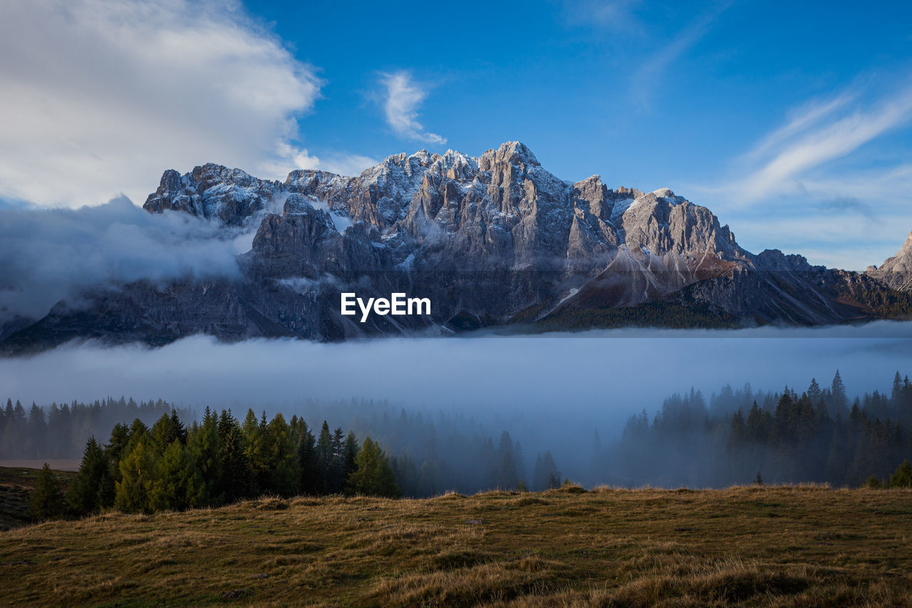 Clouds and fog at dawn from which the wonderful peaks of the dolomites of sesto spring up, italy
