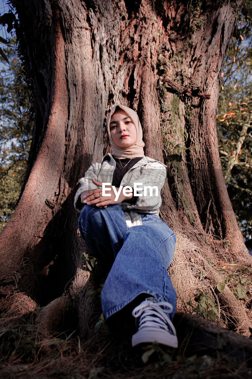 Portrait of women sitting on tree trunk