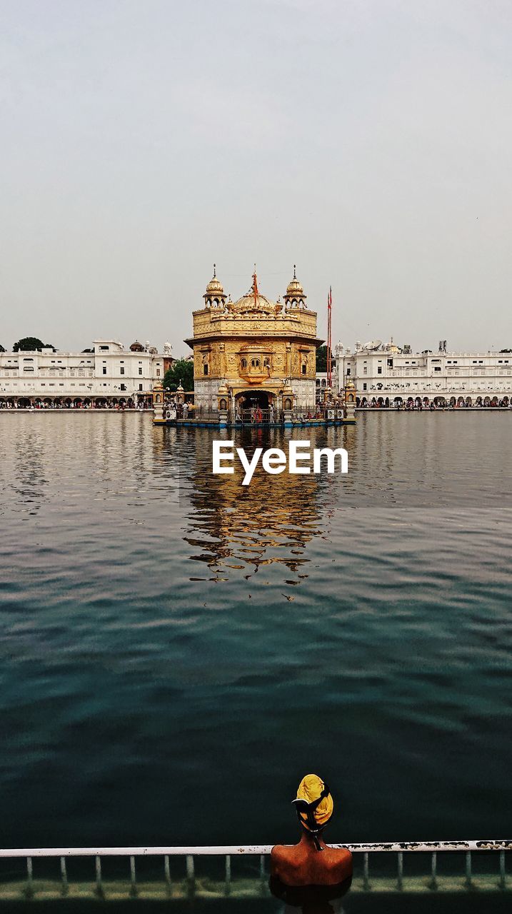 Golden temple by pond against sky