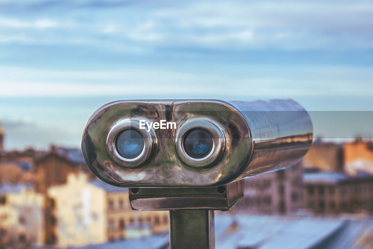 CLOSE-UP OF COIN-OPERATED BINOCULARS AGAINST CLOUDY SKY