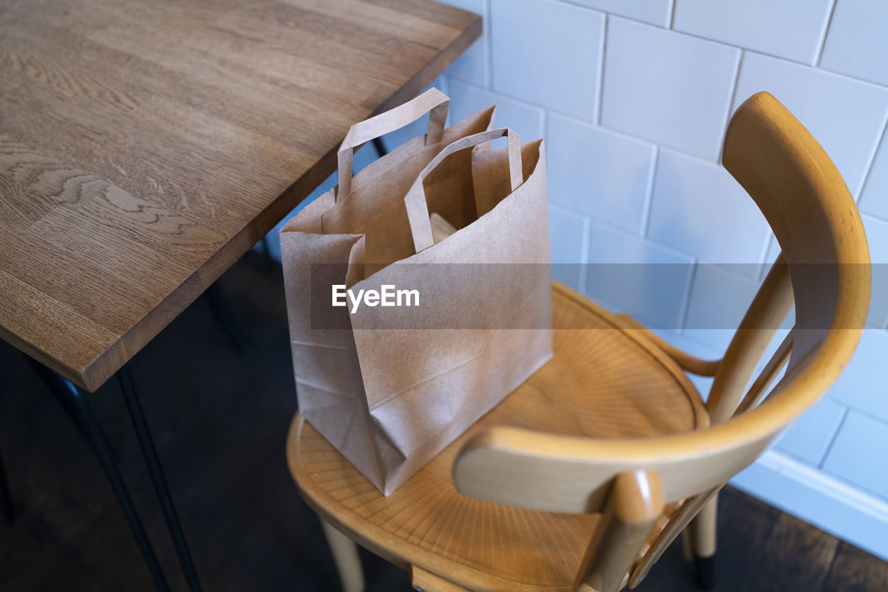 High angle view of empty chair with a paper bag on and table at coffee shop 