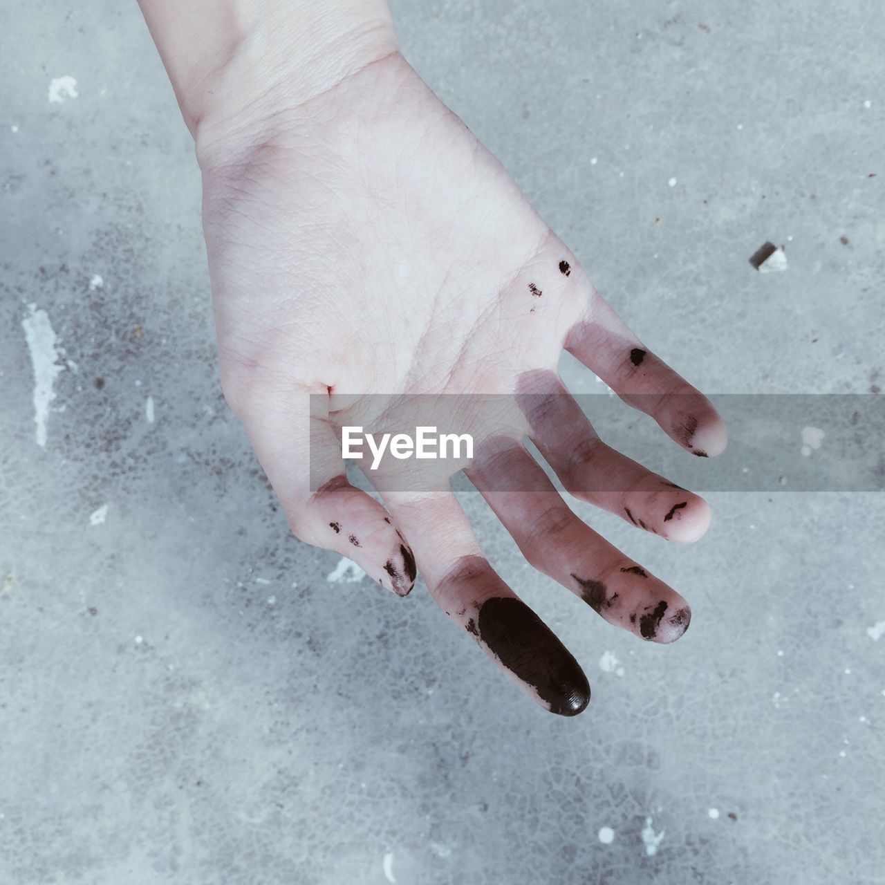 Cropped hand with black paint over floor