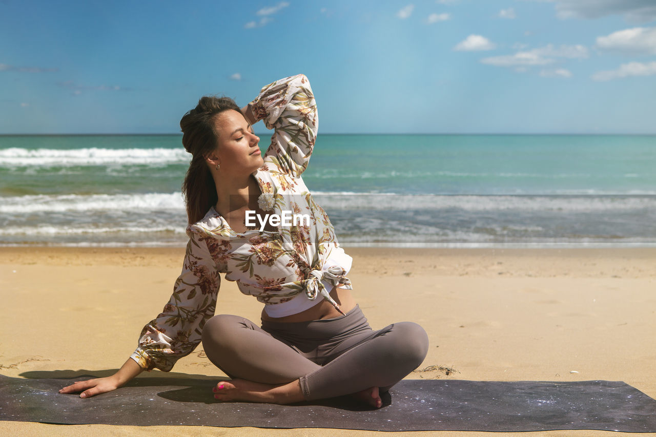Young blond woman on the beach doing pilates, yoga