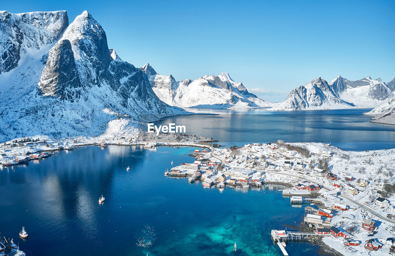 AERIAL VIEW OF SEA BY SNOWCAPPED MOUNTAIN AGAINST SKY