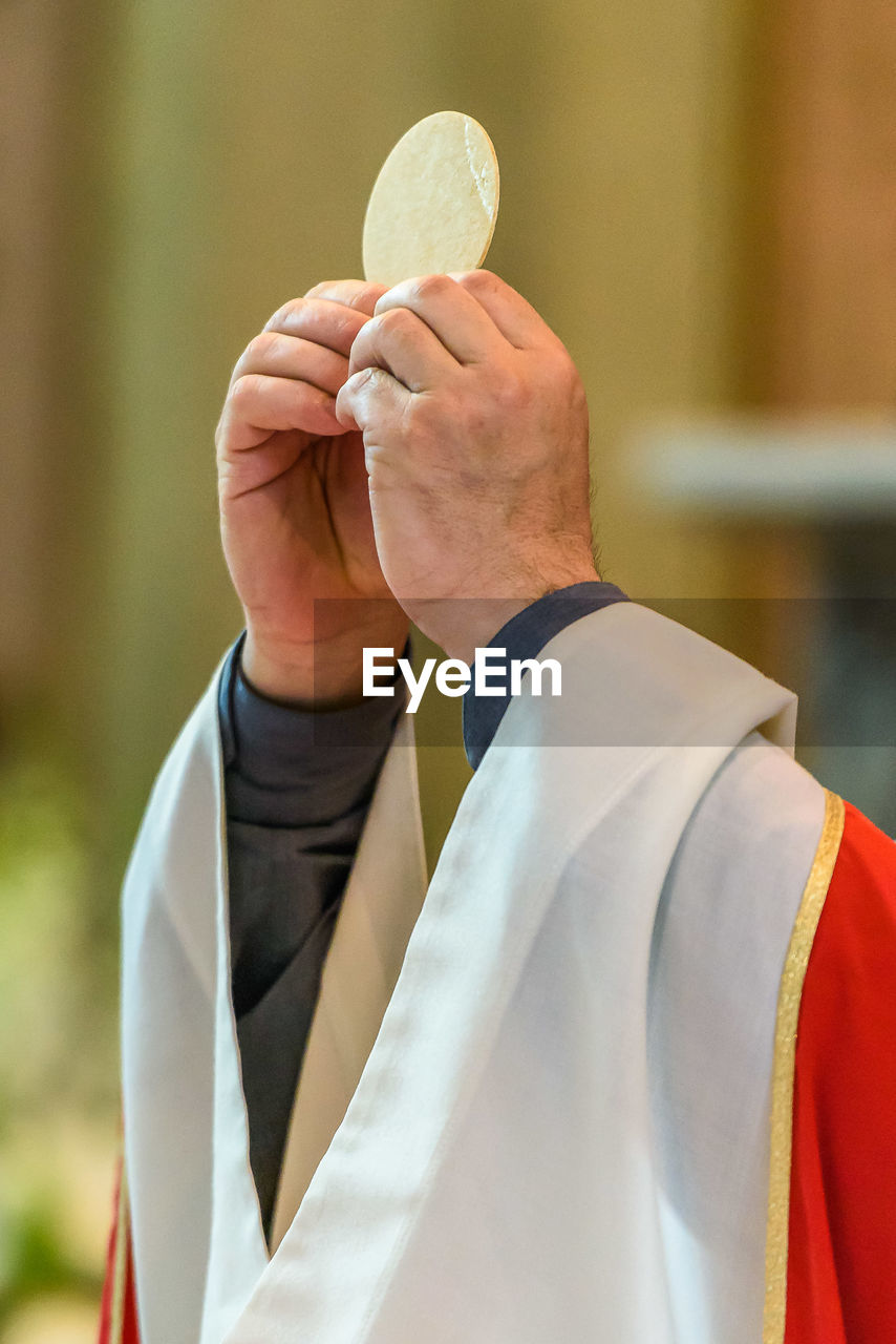 Cropped hands of priest holding bread in church