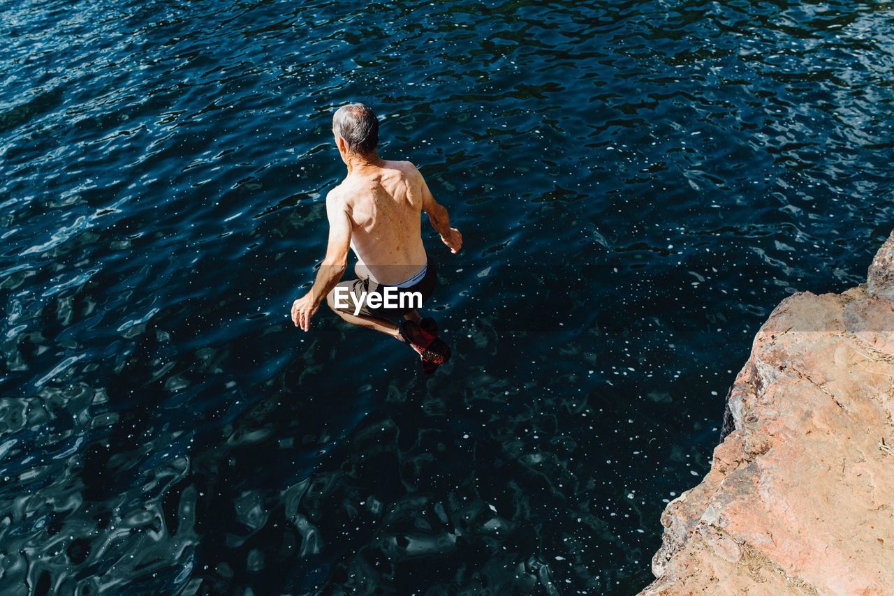 High angle view of man jumping into the sea