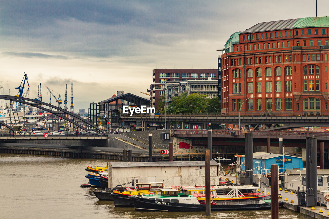Bridge over river by buildings in city against sky