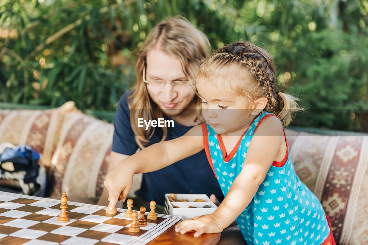 Girl playing chess with father