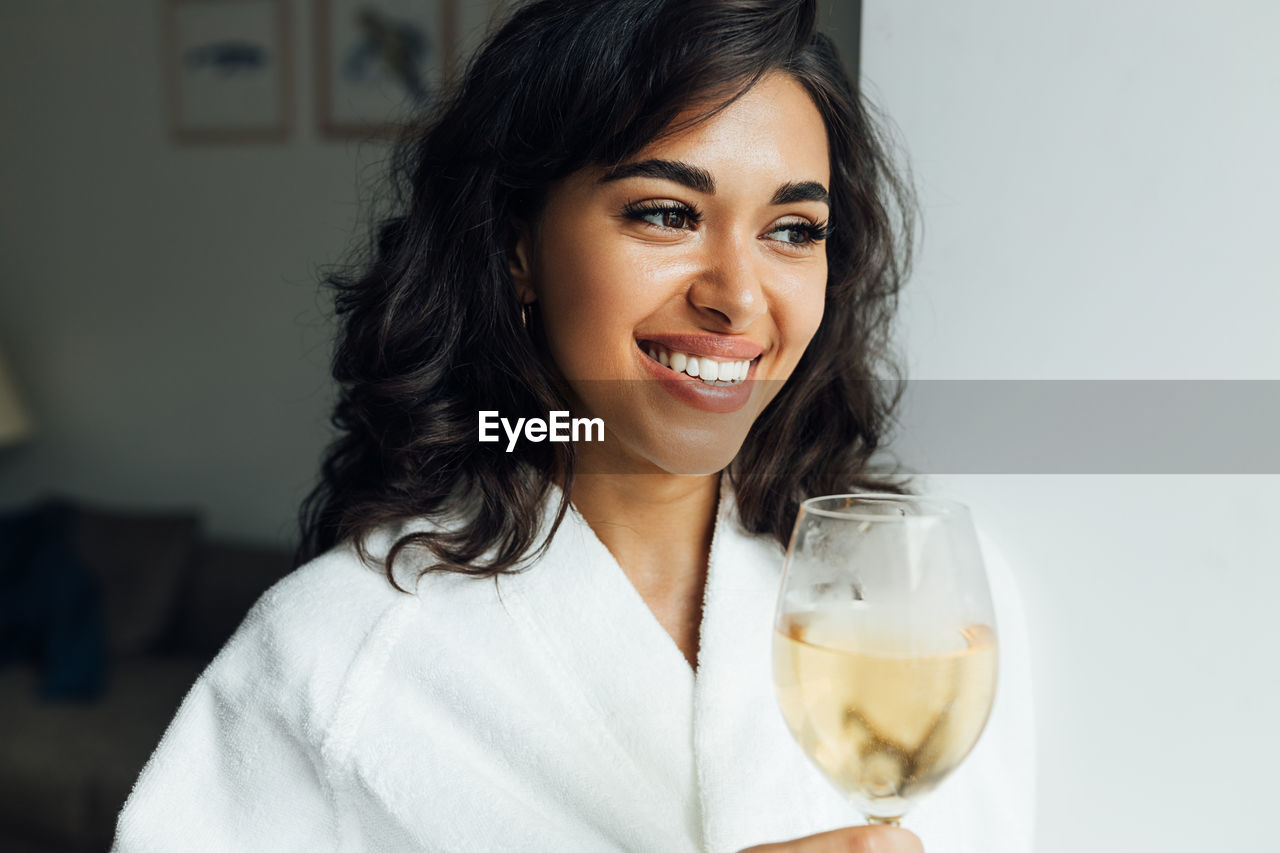 Smiling young woman holding wine at home