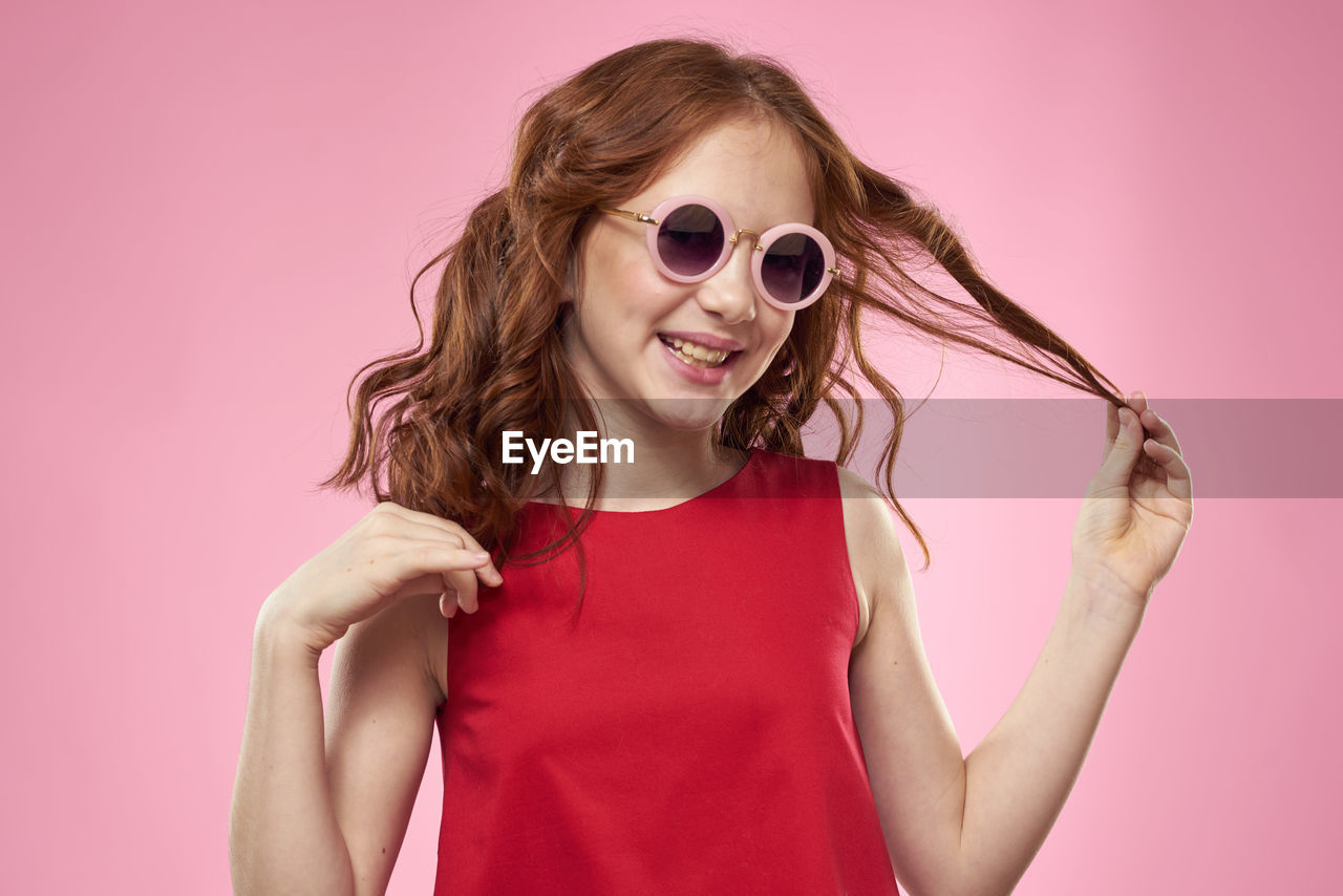 portrait of young woman wearing sunglasses while standing against yellow background