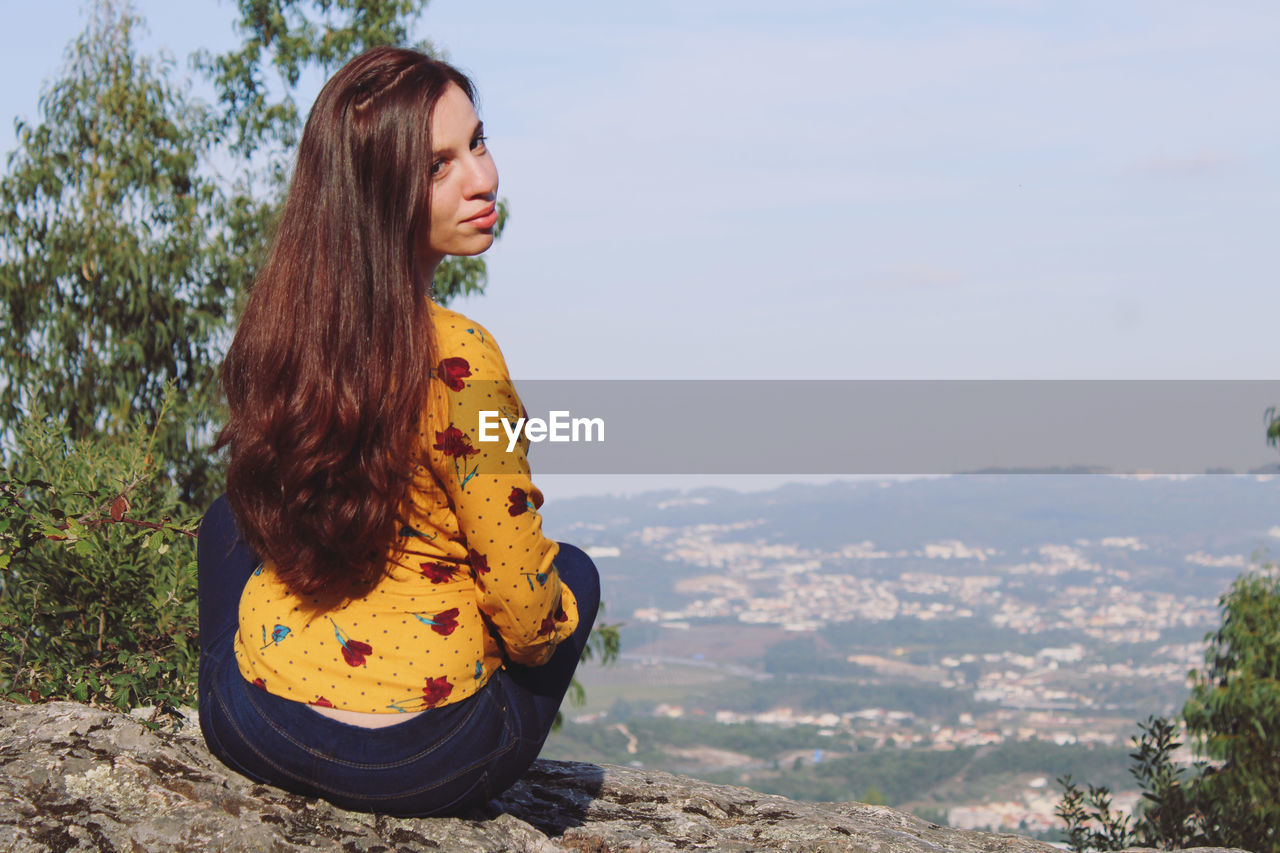 Young woman looking at mountains against sky