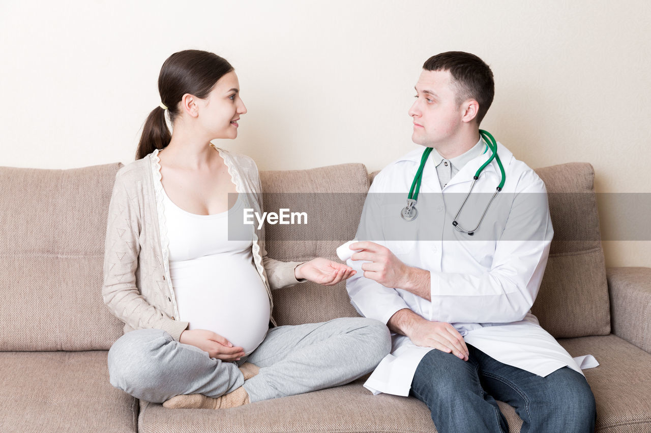 Doctor is giving pills to a pregnant woman and explaining how to use them. treatment 