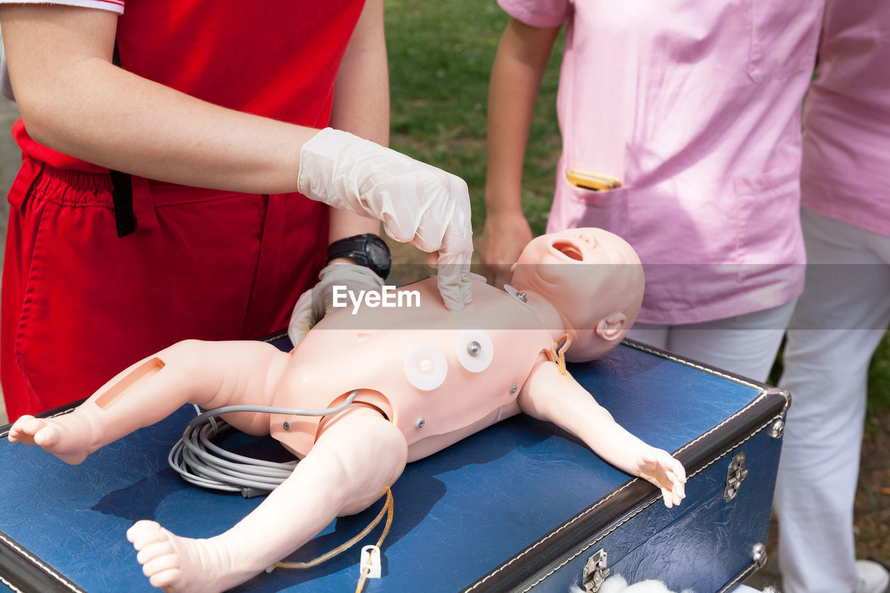 Midsection of paramedics practicing on cpr dummy