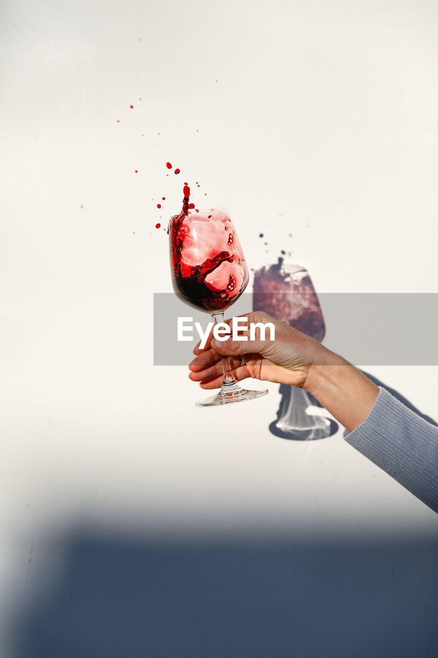 Person holding a glass of red wine