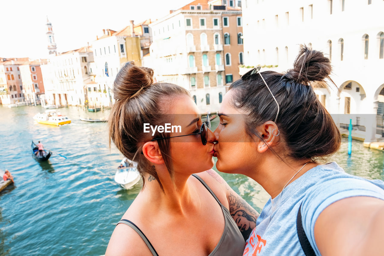 Lesbian couple kissing against buildings