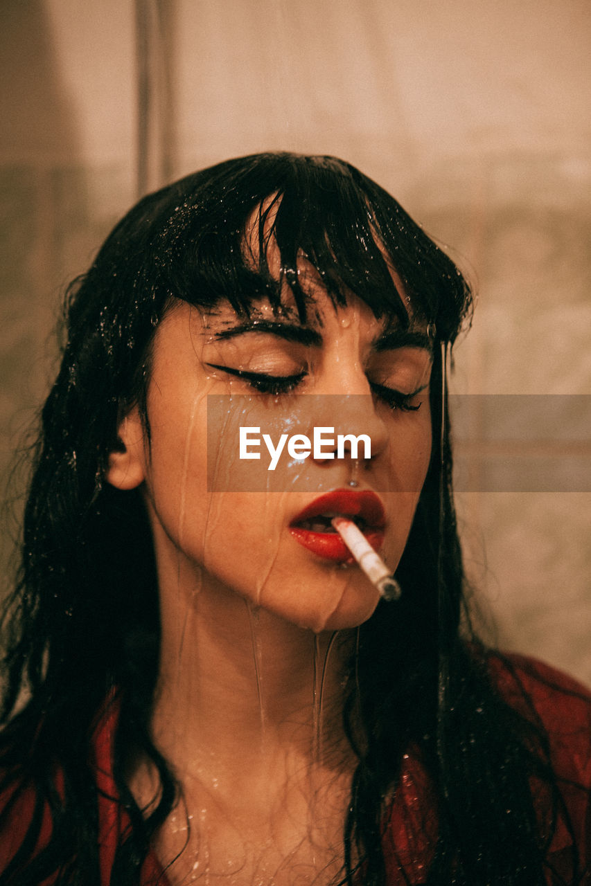 Close-up of wet woman smoking cigarette in bathroom