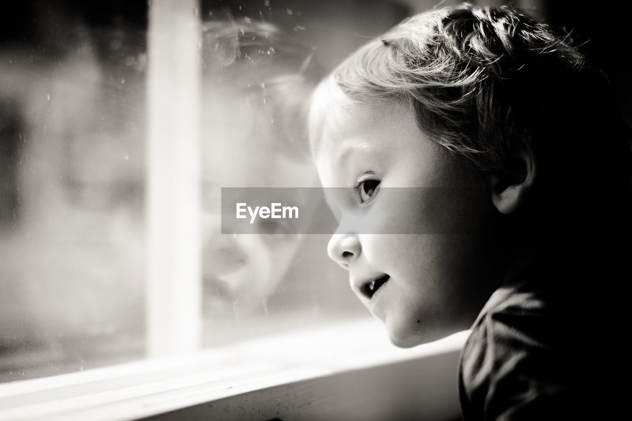 Close-up portrait of boy looking through window