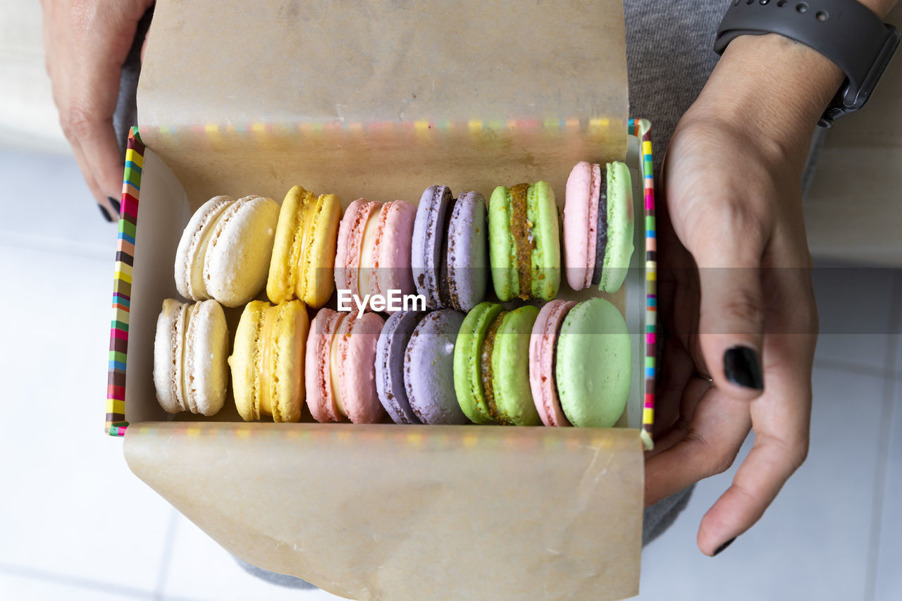 Midsection of woman holding macaroons in box