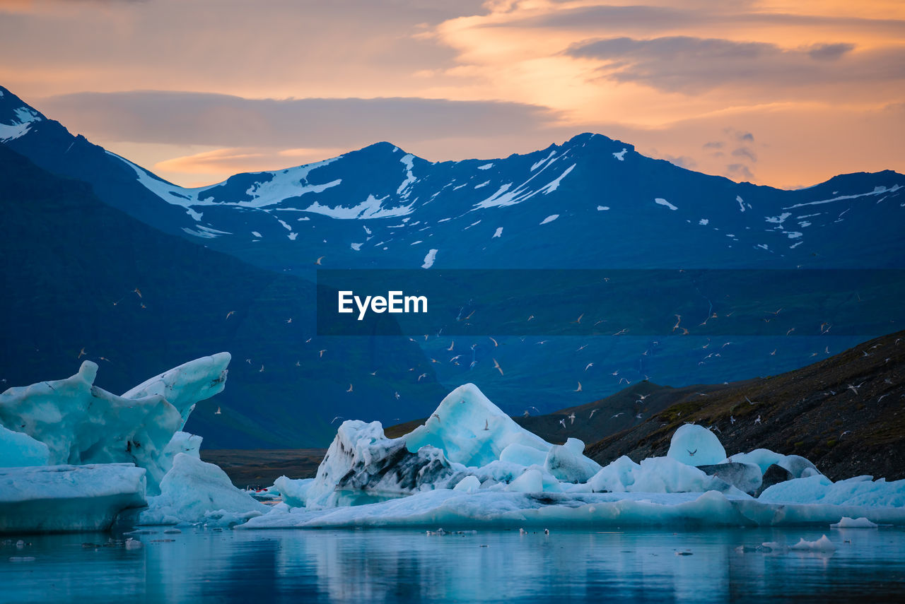 Scenic view of icebergs on lake against sky during sunset