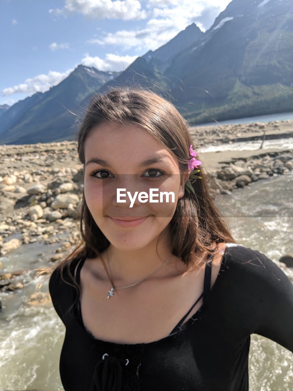 Portrait of smiling young woman standing against mountain
