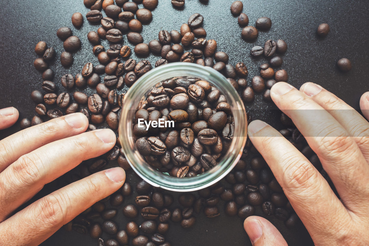 Cropped image of hand holding coffee beans on table