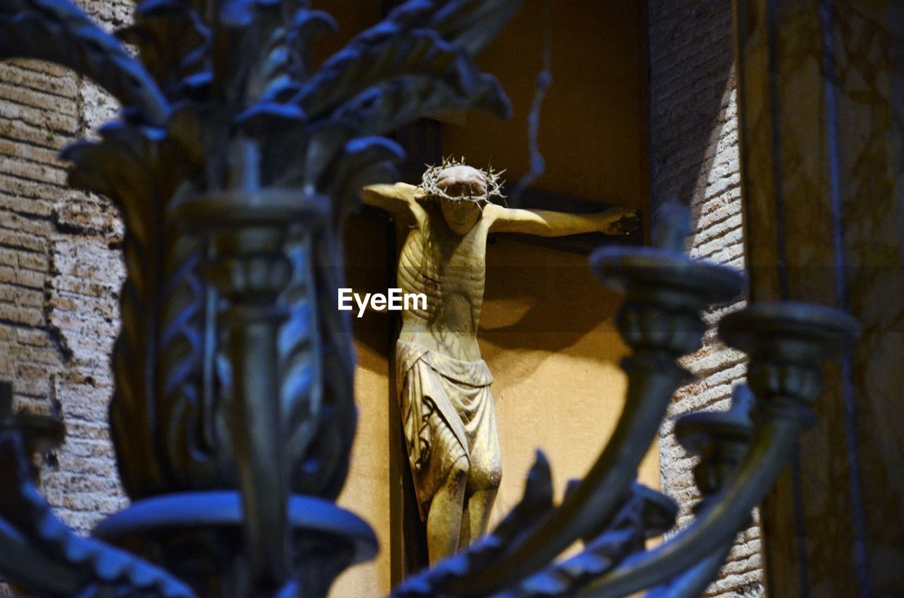 Statue of jesus christ in church viewed through candlestick holder