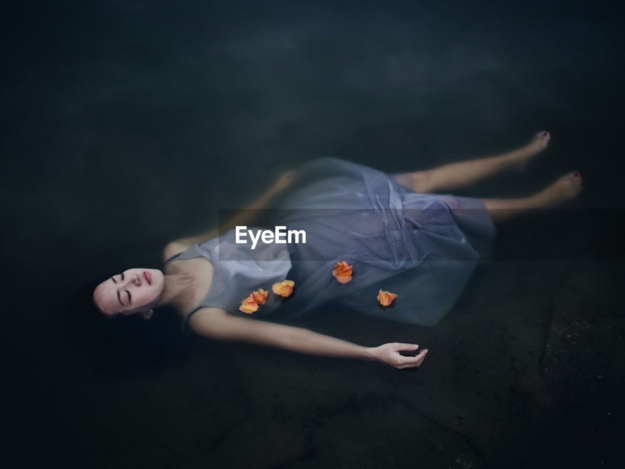 High angle view of young woman with eyes closed floating on lake