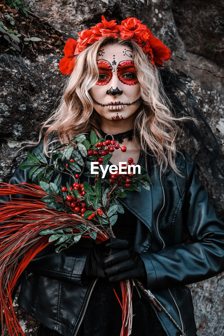 Closeup portrait of calavera catrina. young woman with sugar skull makeup and red flowers. dia