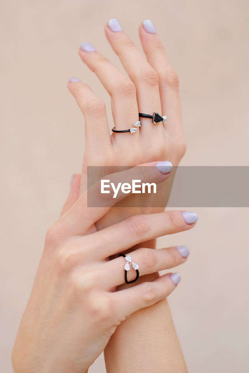 Close-up of hands wearing rings against wall