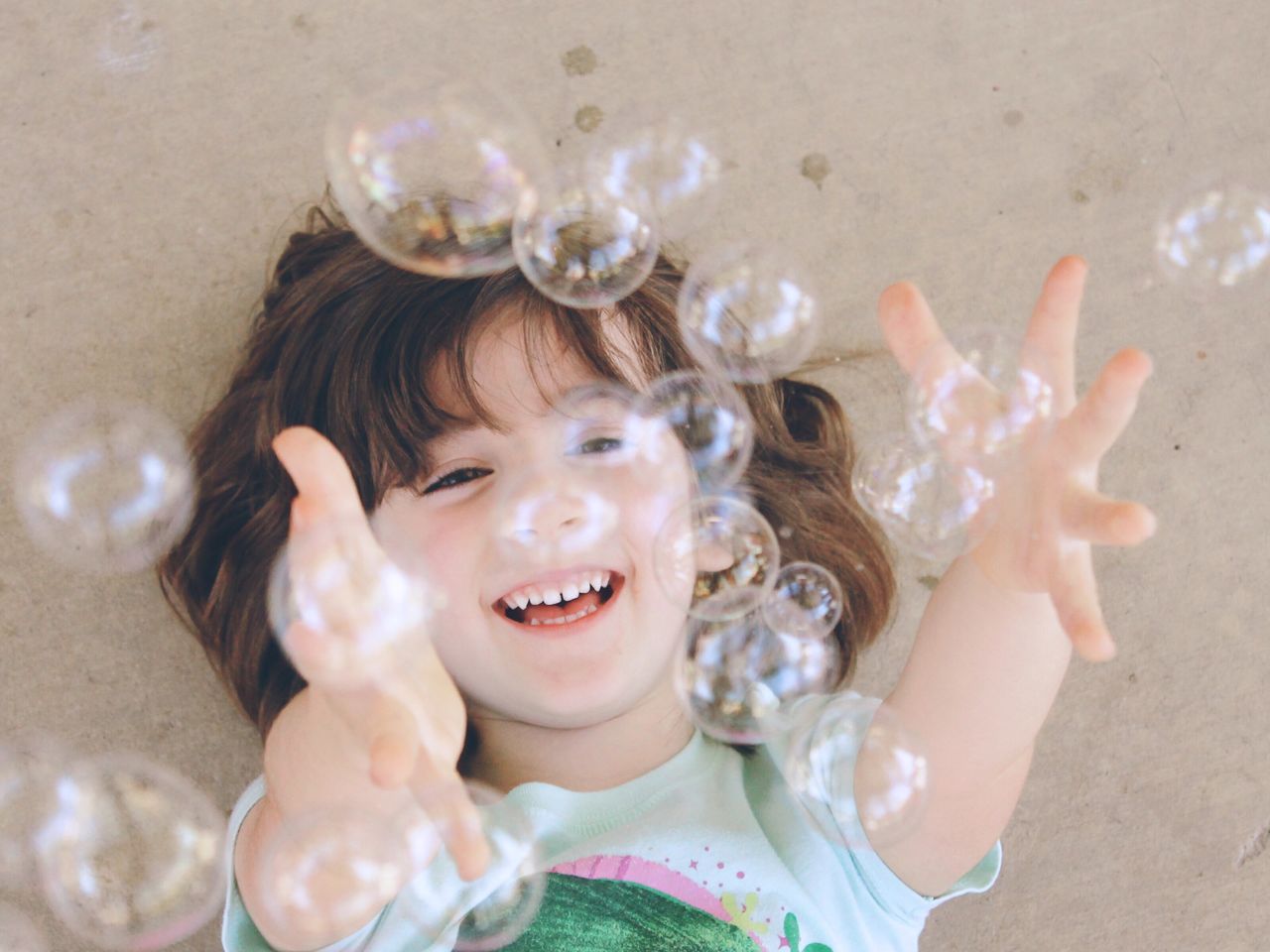 Close-up portrait of smiling girl playing with bubbles