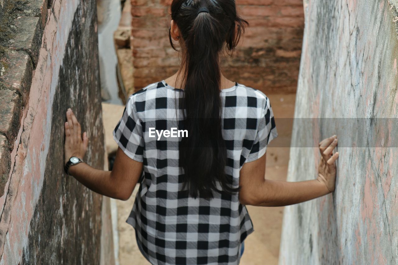 Rear view of teenage girl standing amidst walls