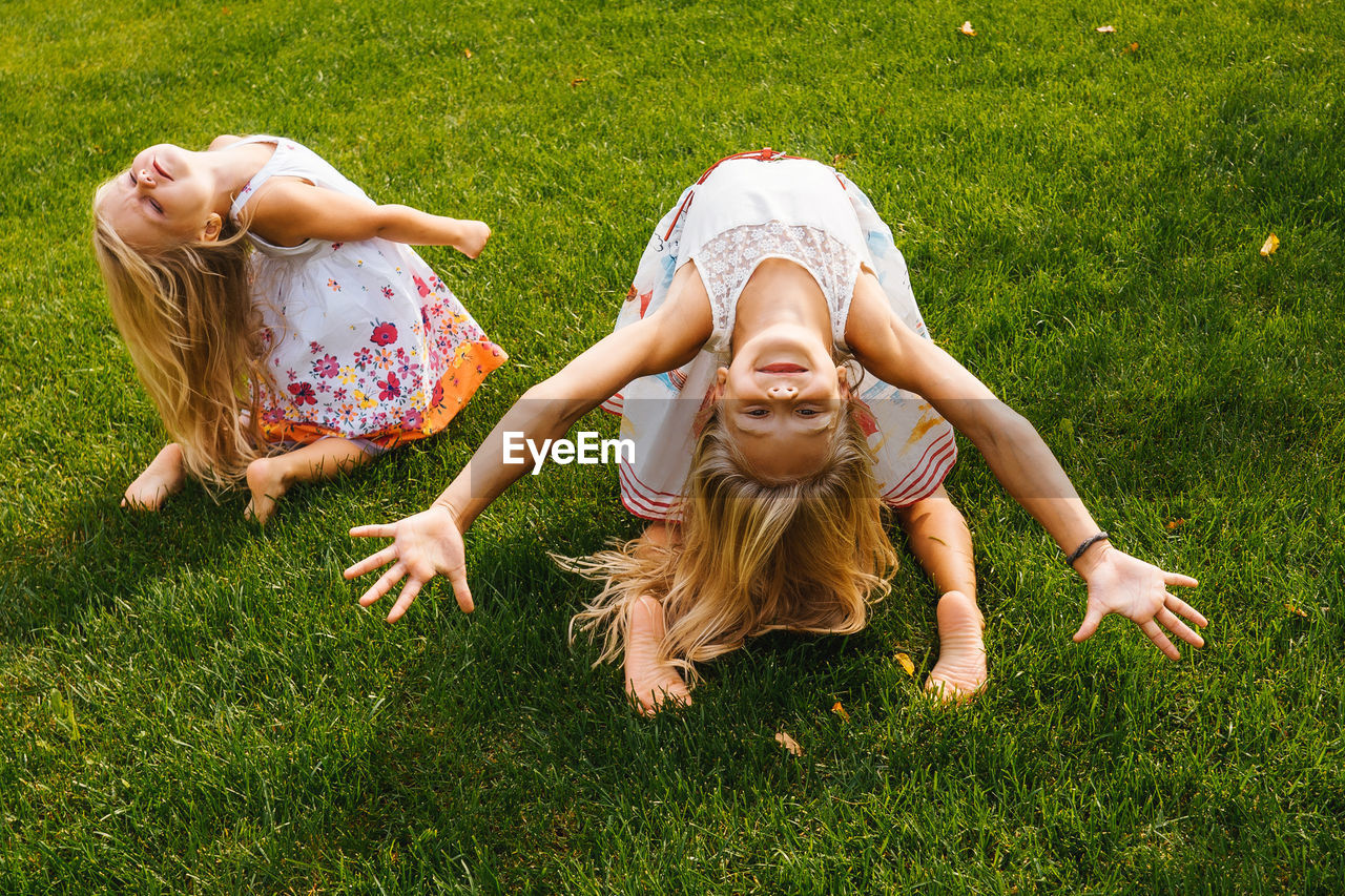 Full length of siblings exercising on grass