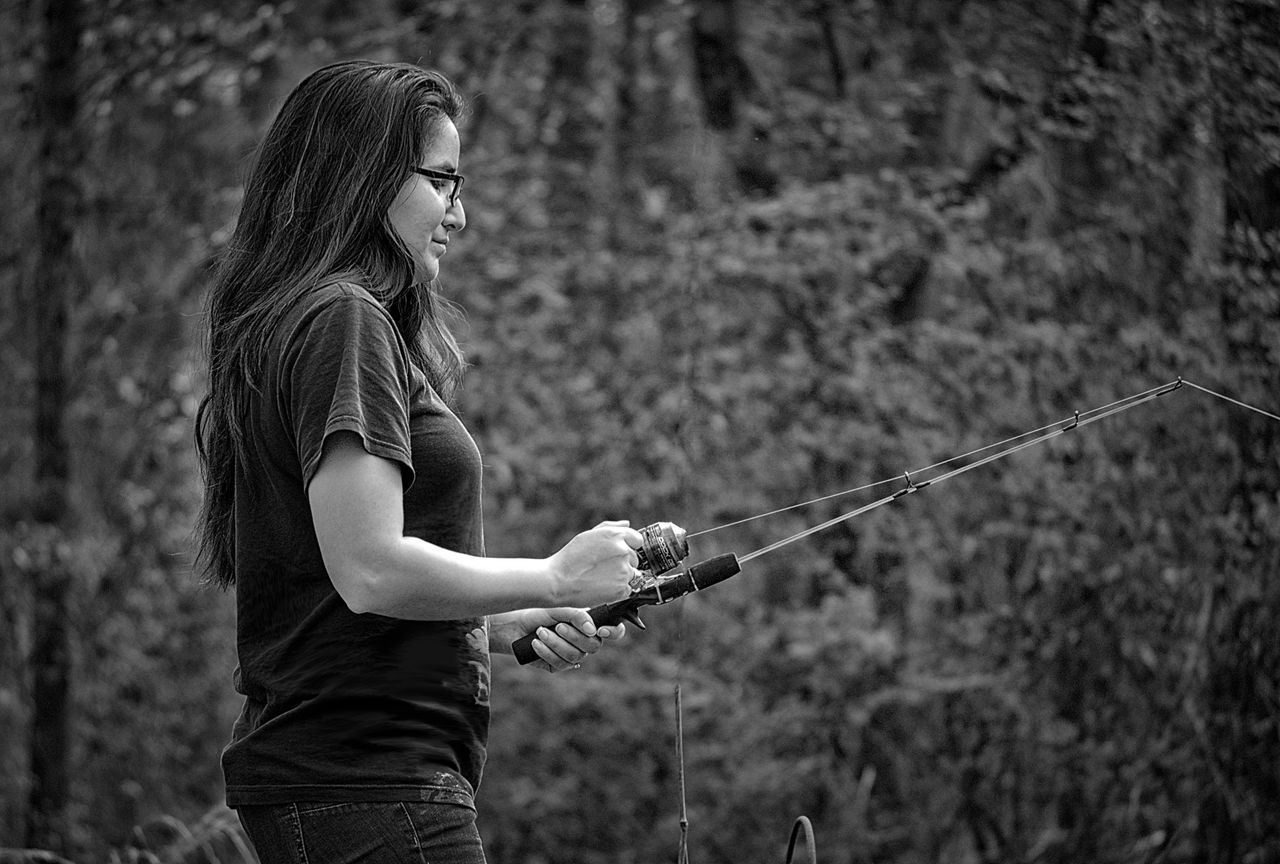 Side view of woman holding fishing rod outdoors