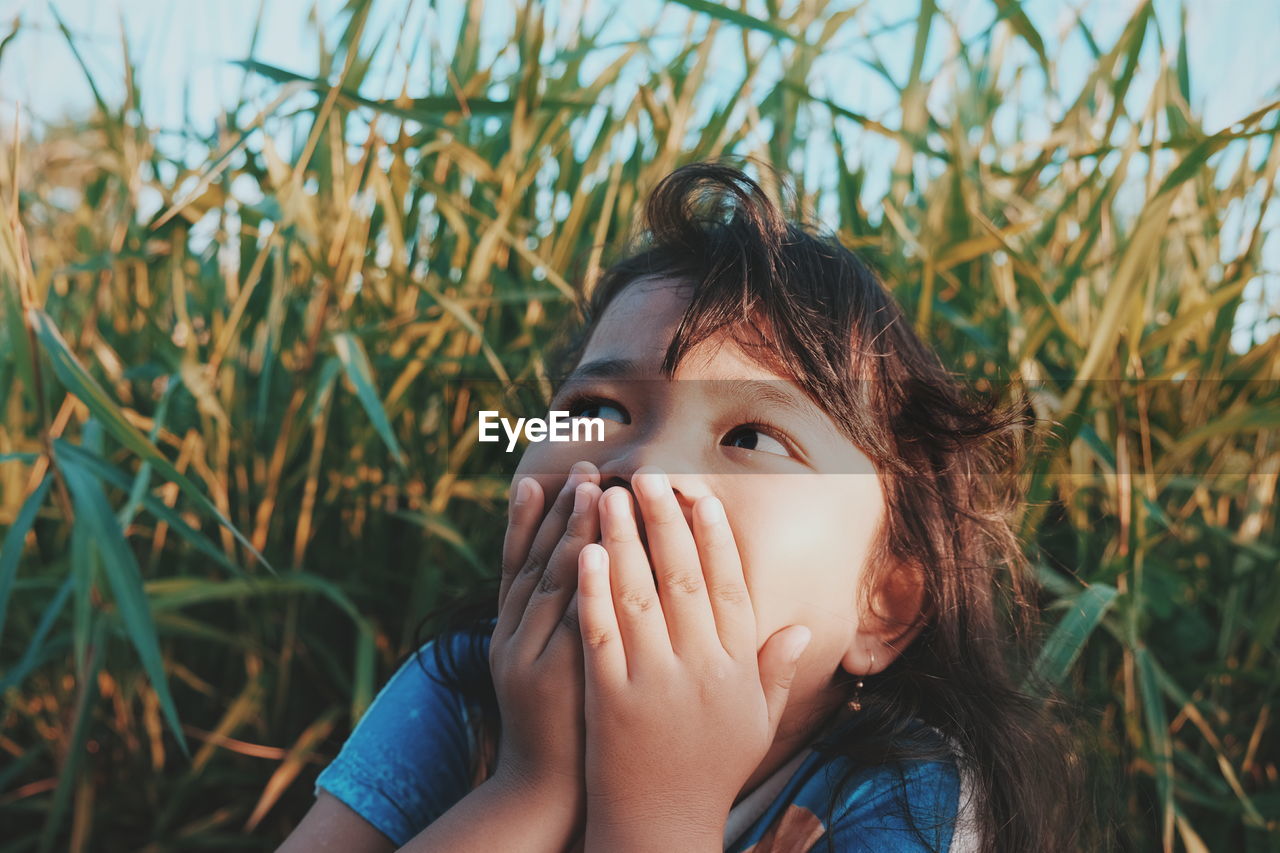 Close-up of girl with hands on mouth