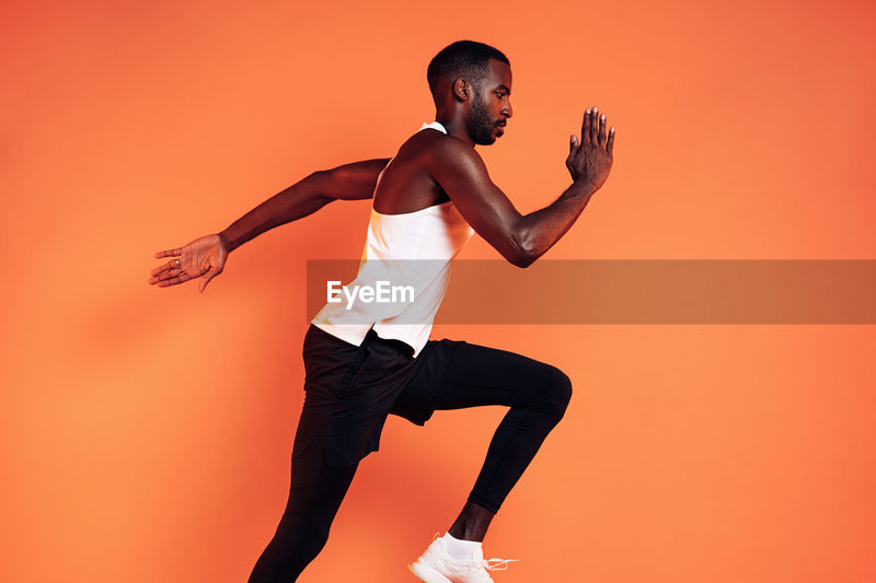 Side view of man running against orange | ID: 181988010