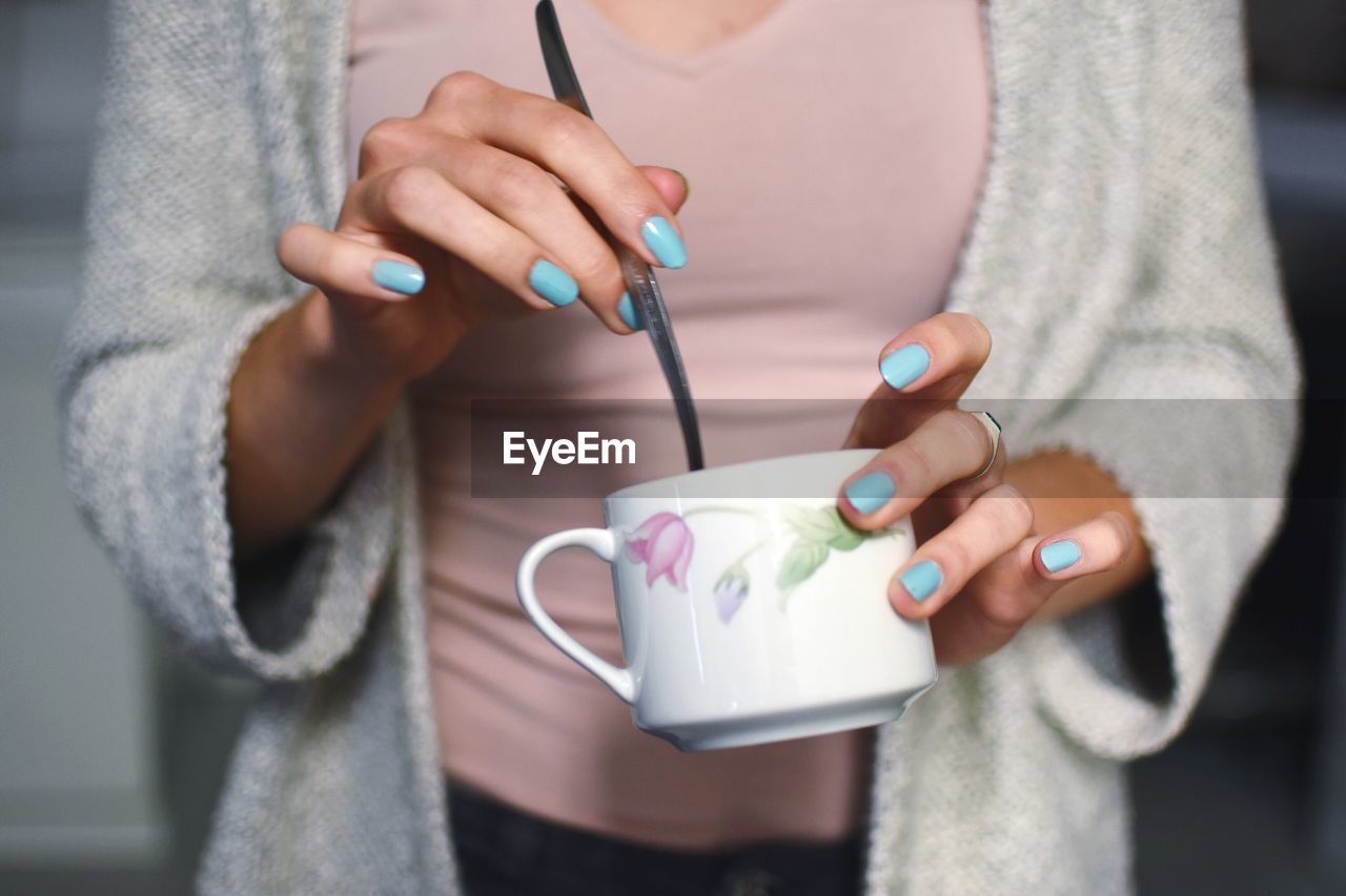 Close-up of woman stirring cappuccino