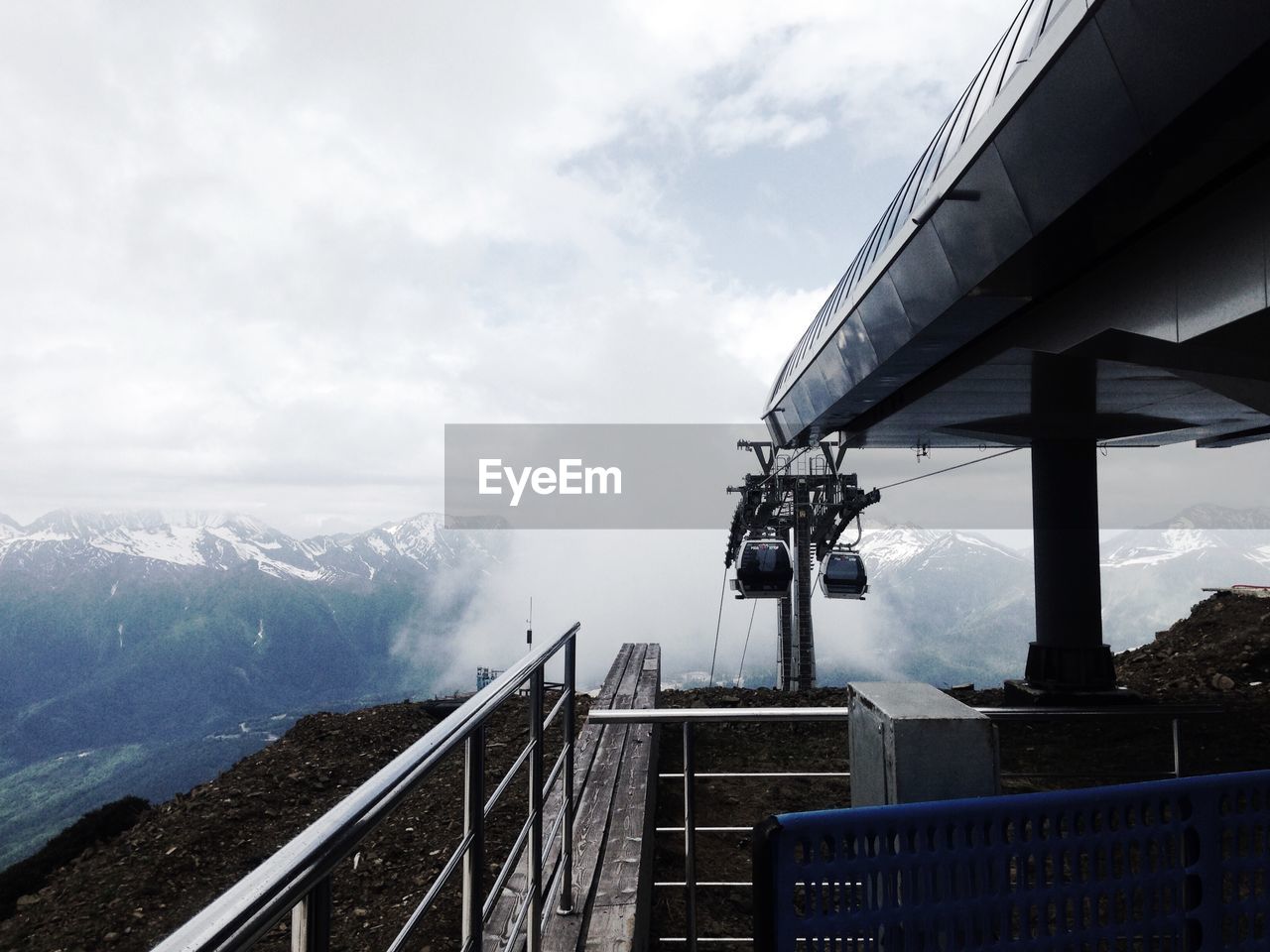 Overhead cable car on snowcapped mountain at ski resort against cloudy sky