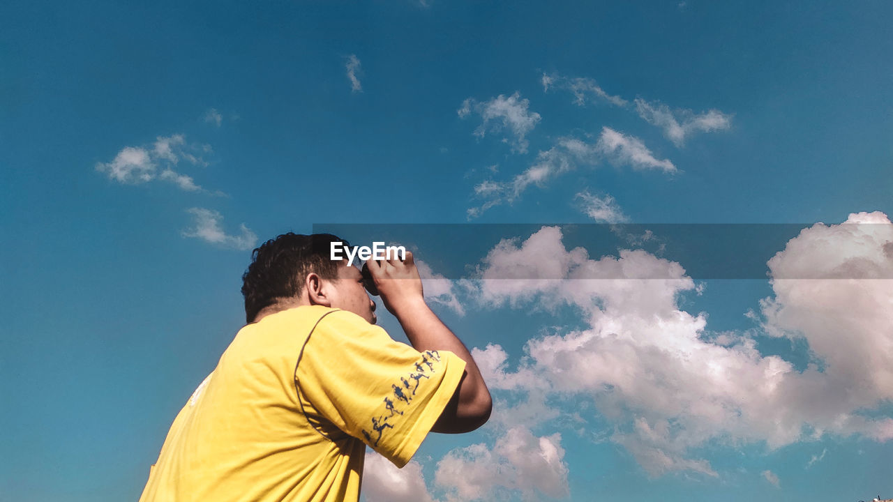 Rear view of man photographing against sky