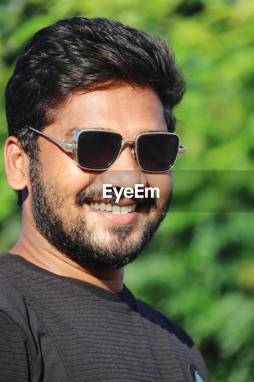 sunglasses, fashion, glasses, portrait, hairstyle, human hair, beard, one person, adult, facial hair, eyewear, men, headshot, vision care, smiling, young adult, happiness, person, cool attitude, casual clothing, emotion, lifestyles, looking at camera, human face, goggles, black hair, outdoors, cheerful, arts culture and entertainment, nature, focus on foreground, clothing, close-up, cool, nose, leisure activity, day, front view
