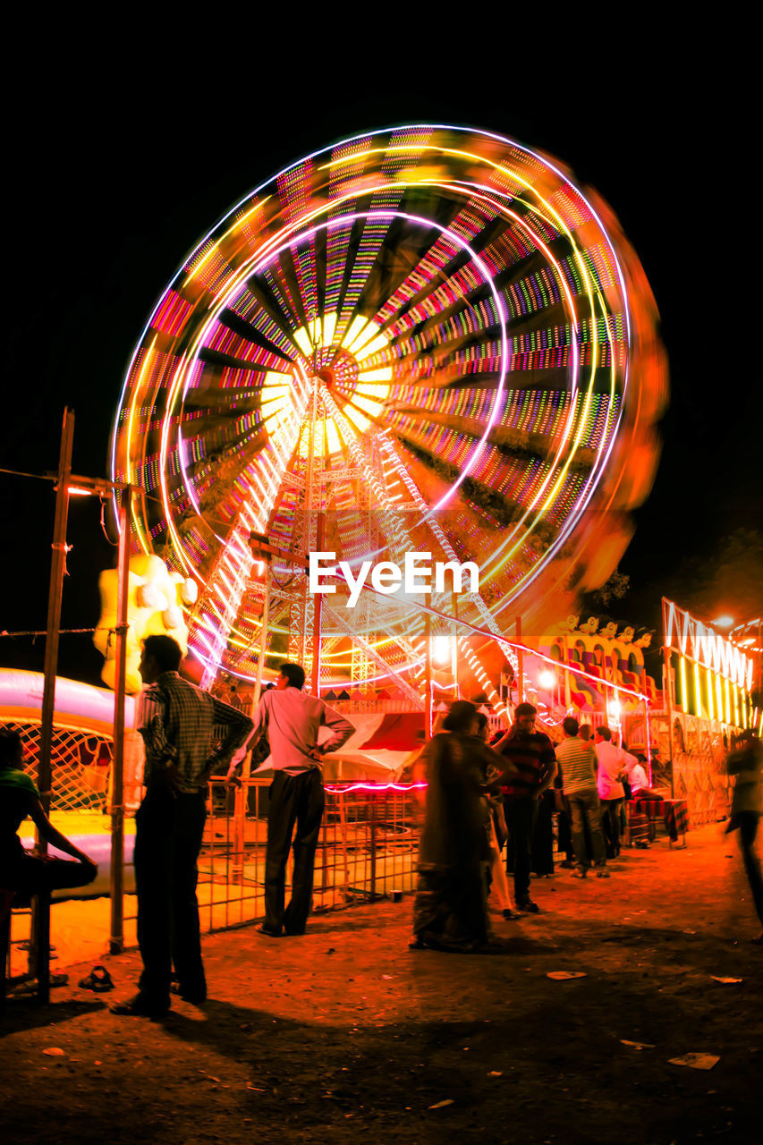 ILLUMINATED FERRIS WHEEL IN AMUSEMENT PARK AT NIGHT